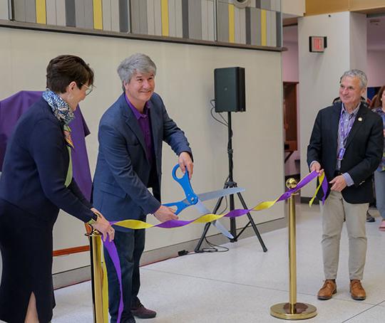 three people, two men and a woman, one cutting a ribbon